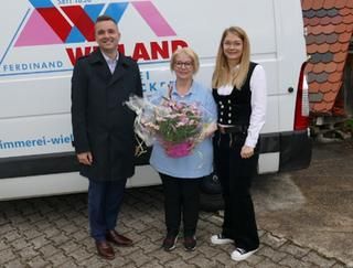 Ein Mann und 2 Frauen stehen vor einem Transporter