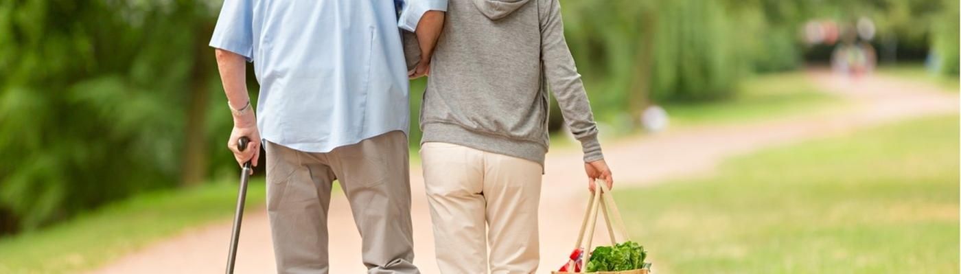 Eine junge Frau hilft einem älteren Mann beim Laufen