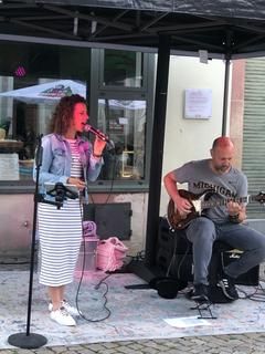 Eine Frau die singt mit einem Mann an der Gitarre.