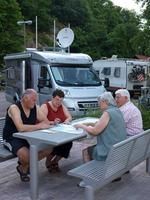 Vier Personen sitzen am Tisch, im Hintergrund die Wohnmobile