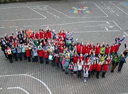 Begeisterte Schüler der Naturparkschule - Foto: Naturpark Schwarzwald Mitte/Nord e.V. Auf dem Schulhof stehen Schüler in einer Wellen-Formation und schauen nach oben zum Fotografen.
