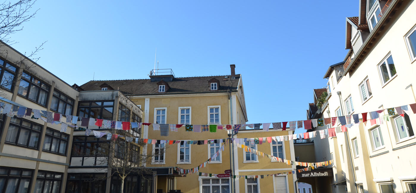 Bunte Stoff-Wimpel an der Laterne vor dem Rathaus