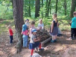 Neben einem Baum spielen Kinder mit Ästen