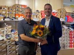 Bürgermeister Julian Christ (rechts im Bild) überreicht Ernst Fischer (links im Bild) einen Blumenstrauß zum 25. Jubiläum.